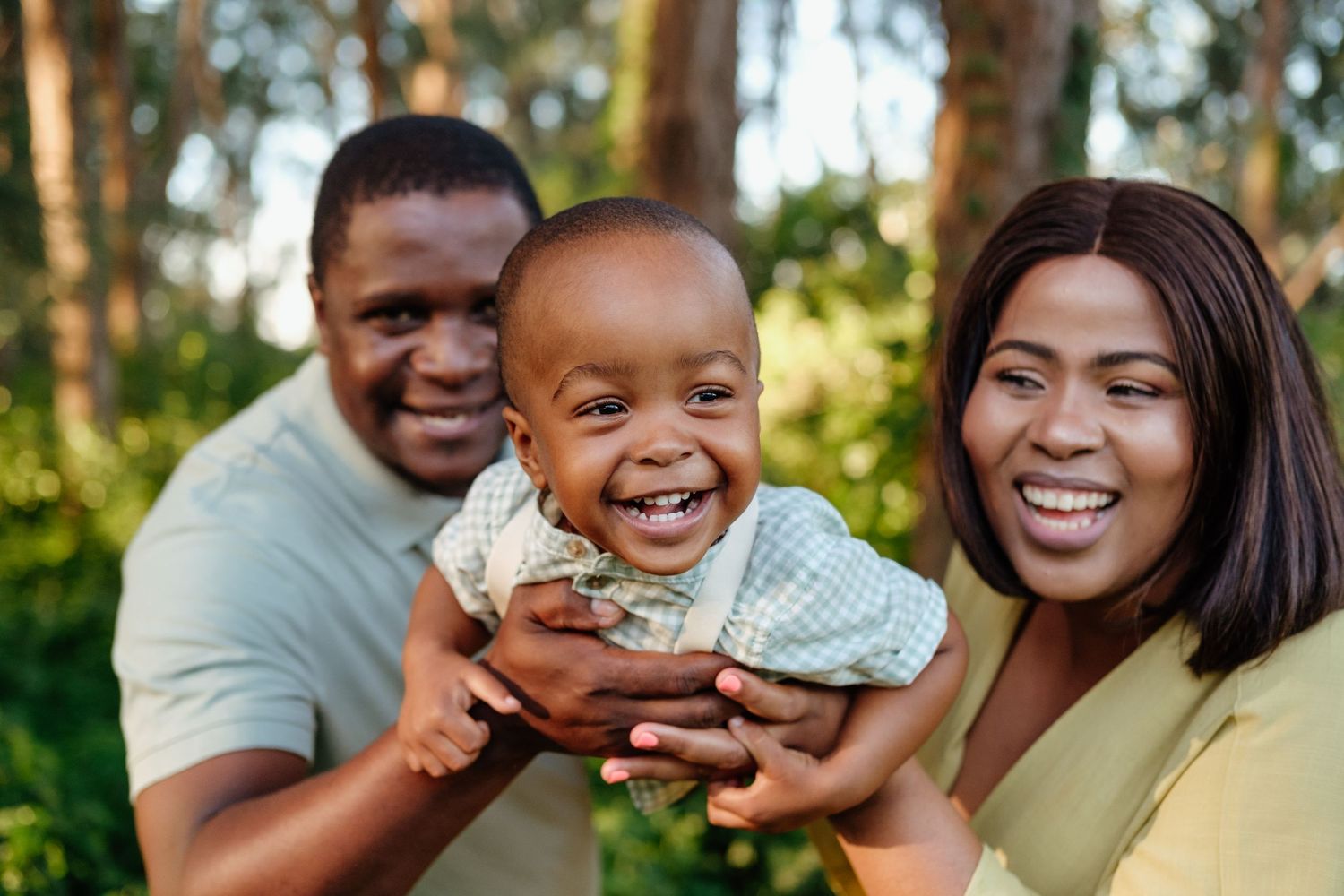 Parents joyfully swinging their baby boy in the air during a lifestyle family photo session