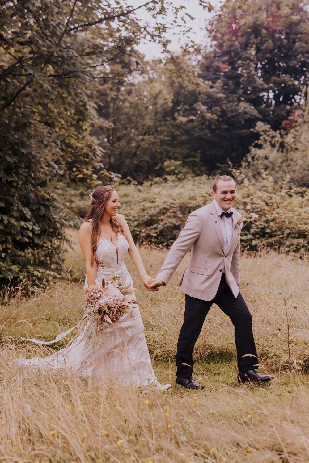 A couple playfully poses in a meadow during their wedding photoshoot.