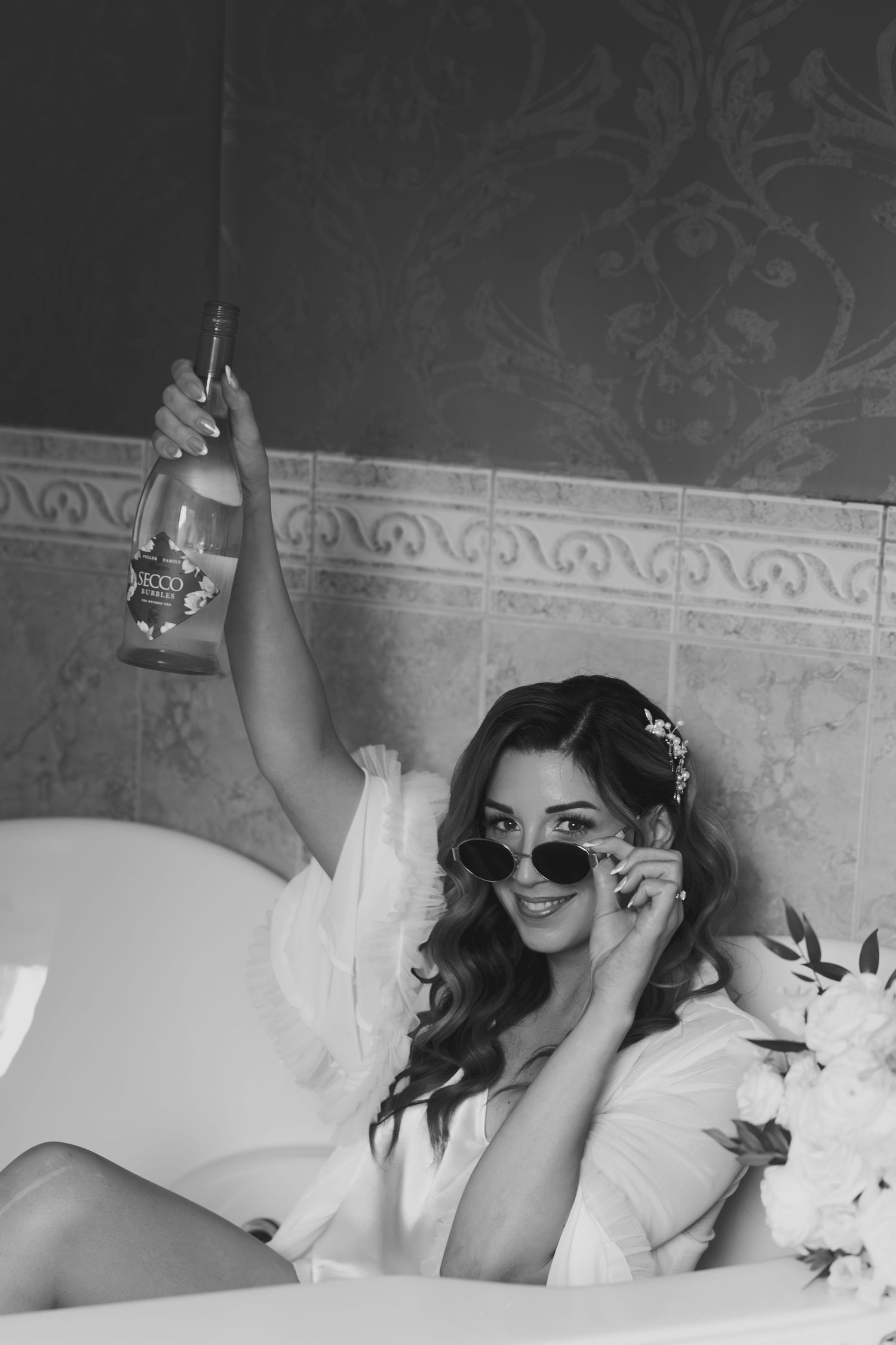 A black and white photo series showing someone lounging on white bedding while wearing sunglasses.