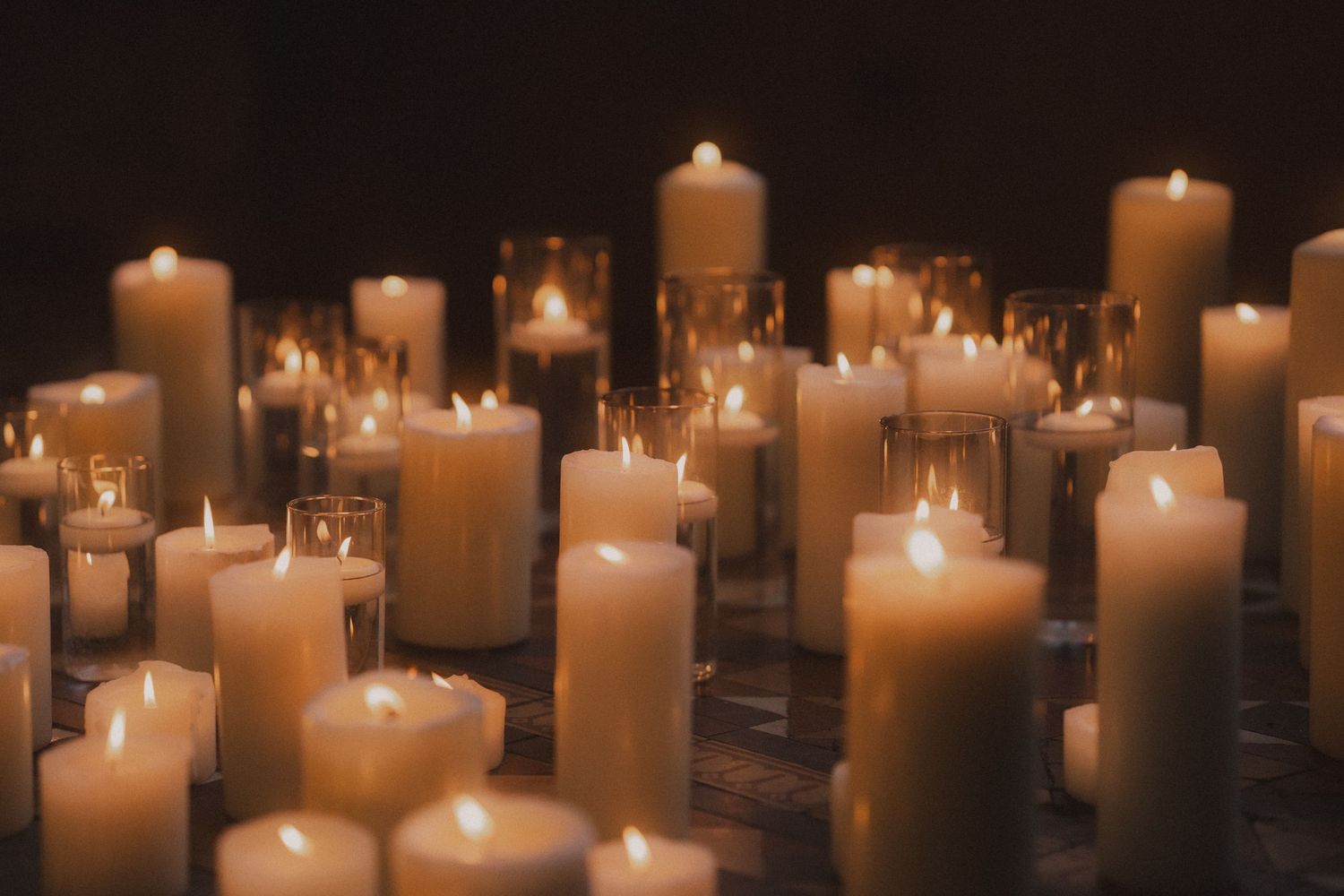 Multiple white candles glowing in the darkness create a serene and peaceful ambiance.
