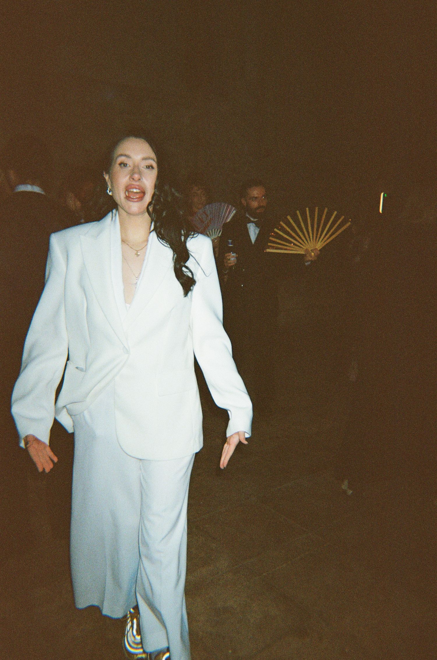 A person wearing a white suit moves across a dark background in a sequence of candid motion shots.