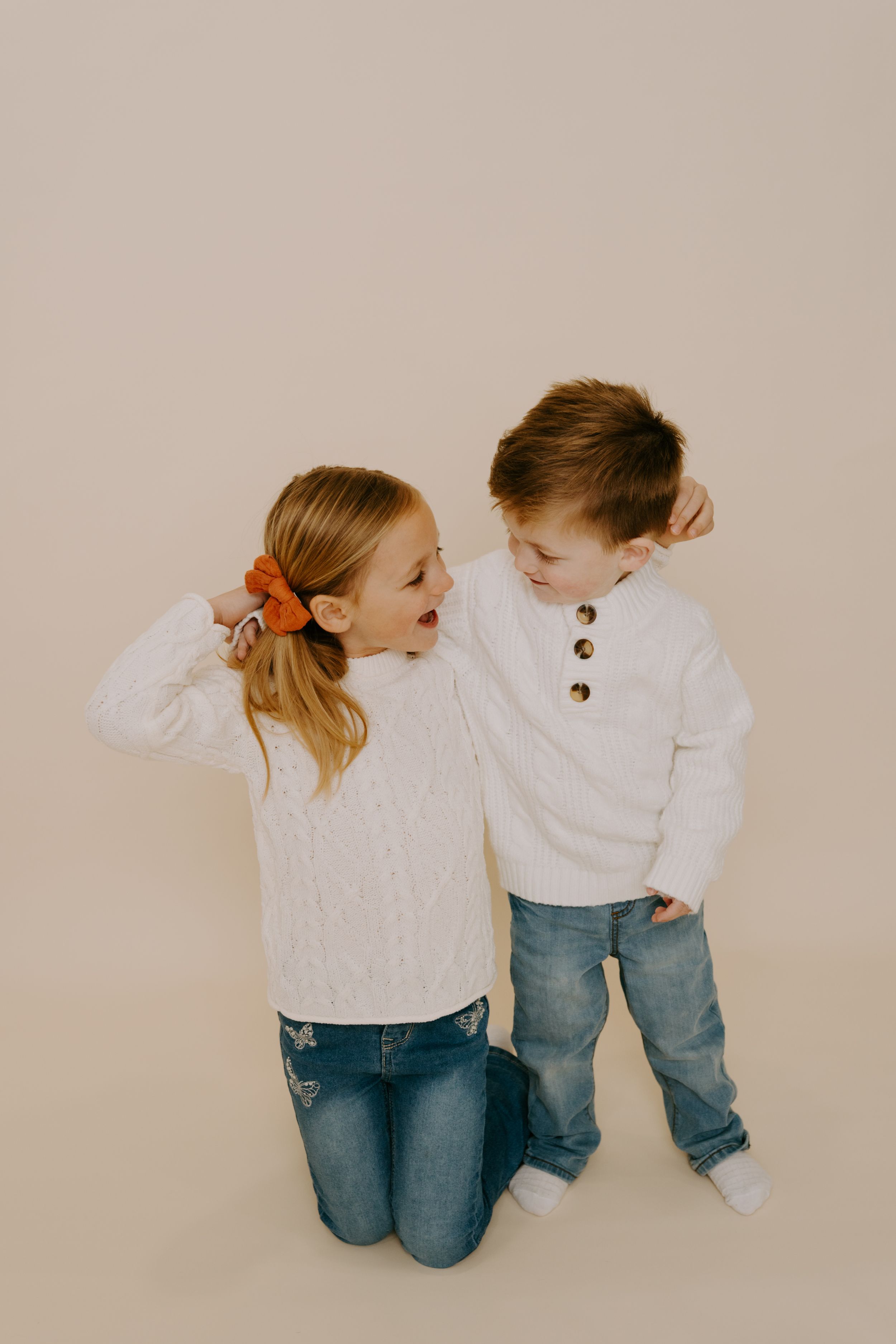 Two people in matching white sweaters playing and posing together.