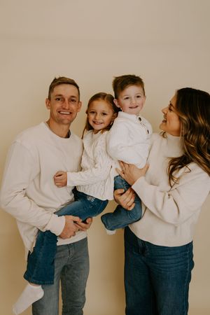 Candid family photo with everyone in matching white sweaters and denim.