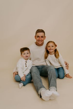 Candid family moment captured during studio photography session with neutral background.