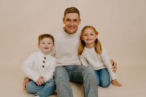 Studio portrait of family group sitting together in coordinated casual outfits.