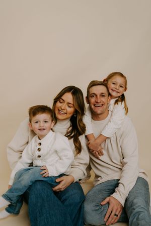 Joyful family portrait with natural expressions and coordinated white and denim outfits.