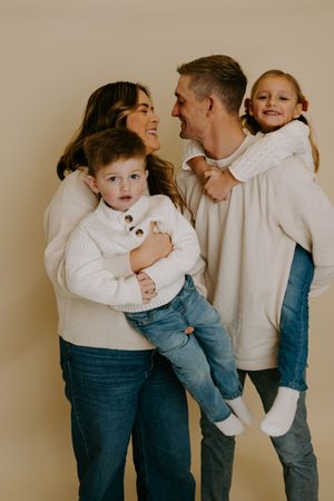 Candid family portrait showing genuine laughter and connection in matching cream and denim outfits.