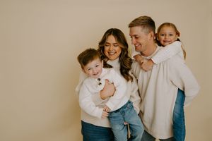 Lifestyle family portraits showing genuine emotion and interaction against a neutral background.