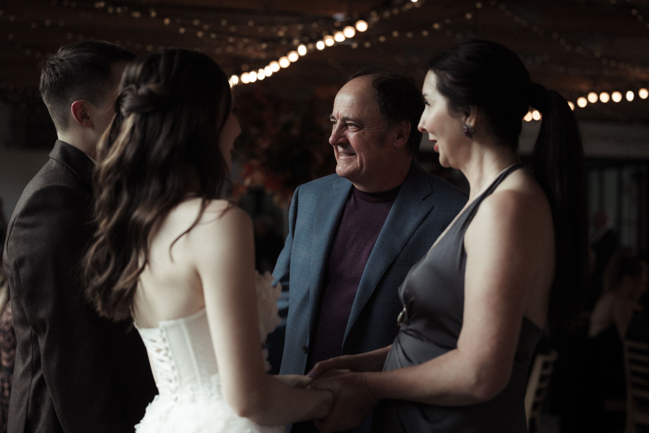 A couple shares a romantic moment during their first dance at a dimly lit wedding reception.