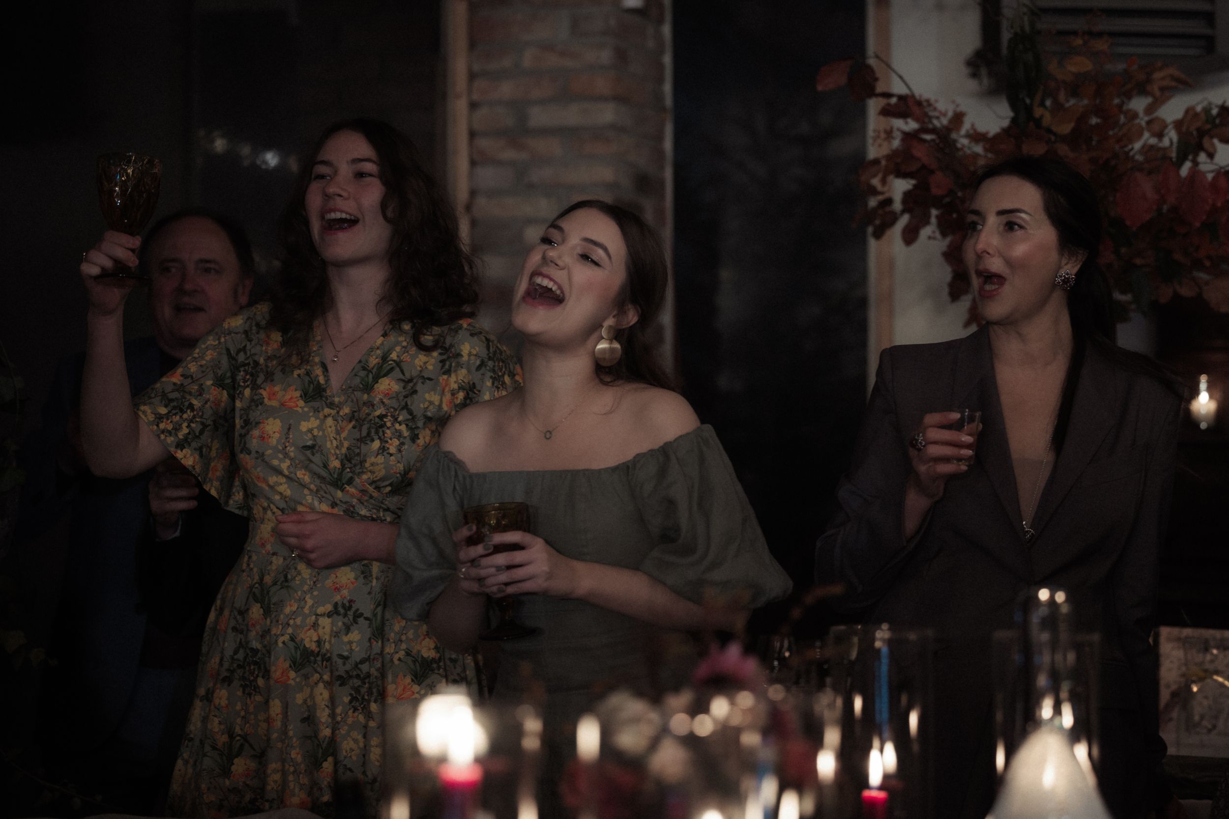 People enjoying a candlelit dinner party with laughter and conversation around a rustic table.