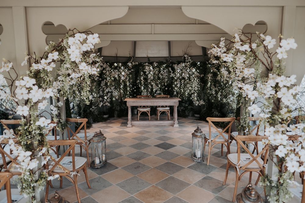 Modern reception space with cross-back chairs and white floral decor creating an airy atmosphere.
