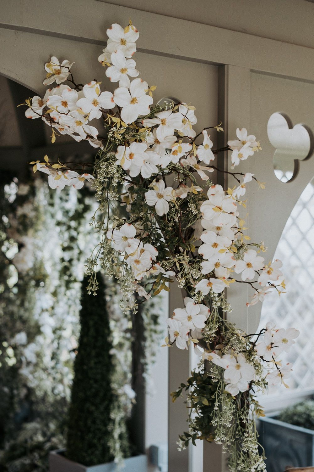 Cascading white orchids and floral arrangements create an elegant ceiling display at an event venue.