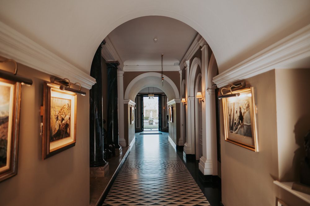 Long elegant hallway with arched ceilings and artwork displayed along cream colored walls.