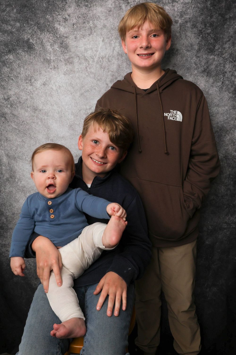 Studio portrait series against textured grey background showing casual family poses.