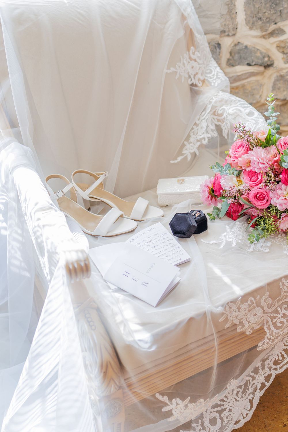 White lace and pink floral wedding decor elements arranged on a light surface with elegant paper details.