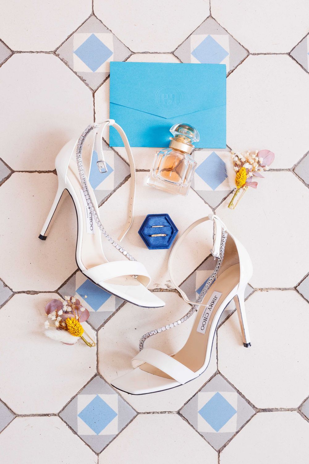 White bridal shoes with crystal details arranged on hexagonal tile floor.