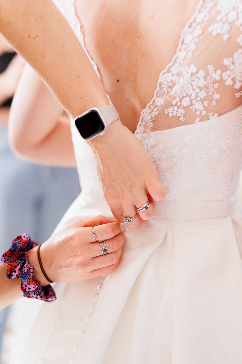 Close-up of wedding dress being fastened with delicate lace details visible.