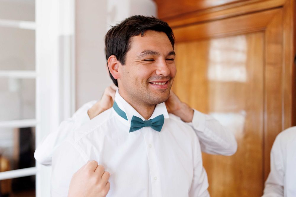 Groomsmen sharing laughs while preparing for wedding in formal wear.