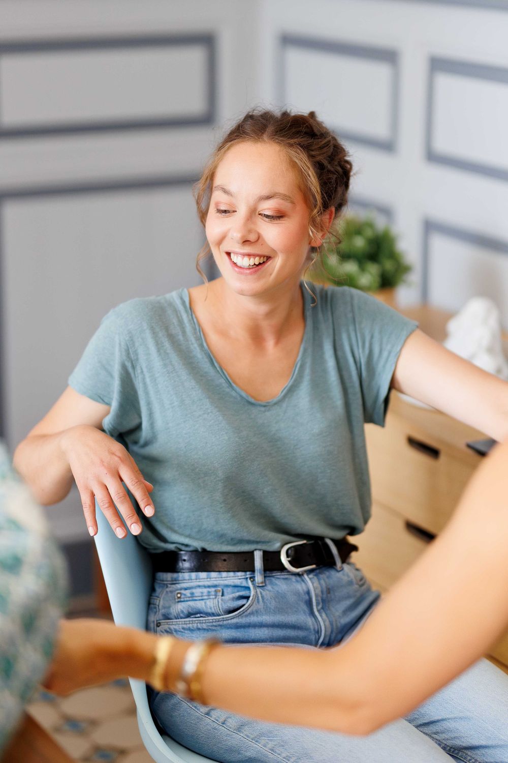 Woman in casual denim and teal shirt sitting relaxed during candid moments.