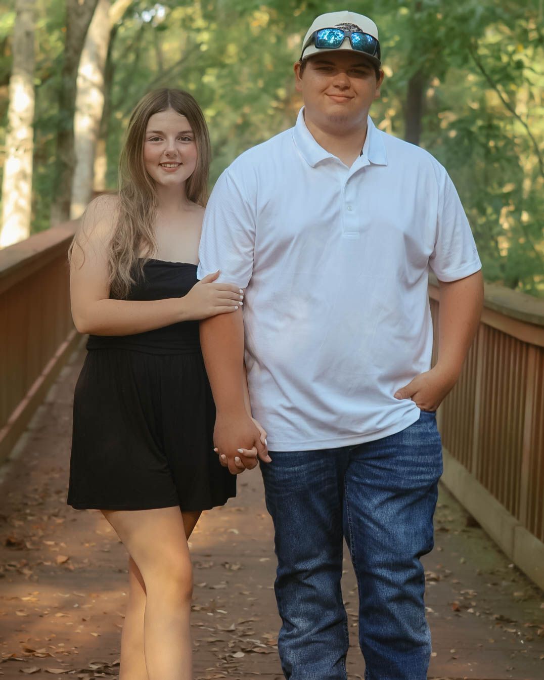 Couple posing together on a wooden walkway in a wooded setting.