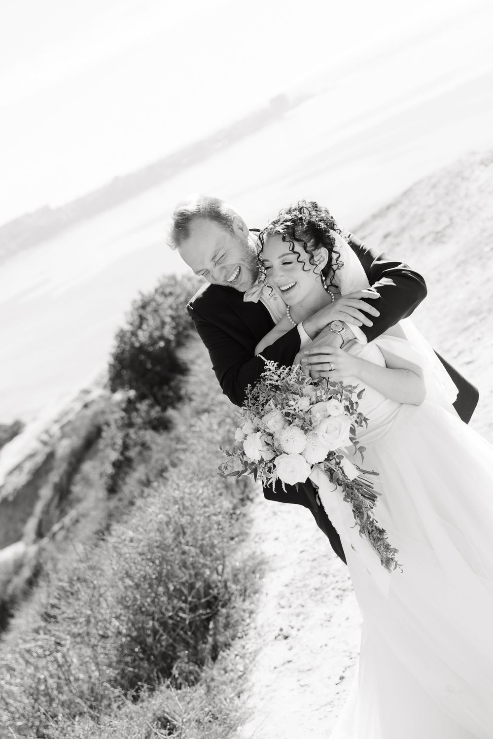 Black and white artistic wedding photos showing tender moments between newlyweds on a hillside.