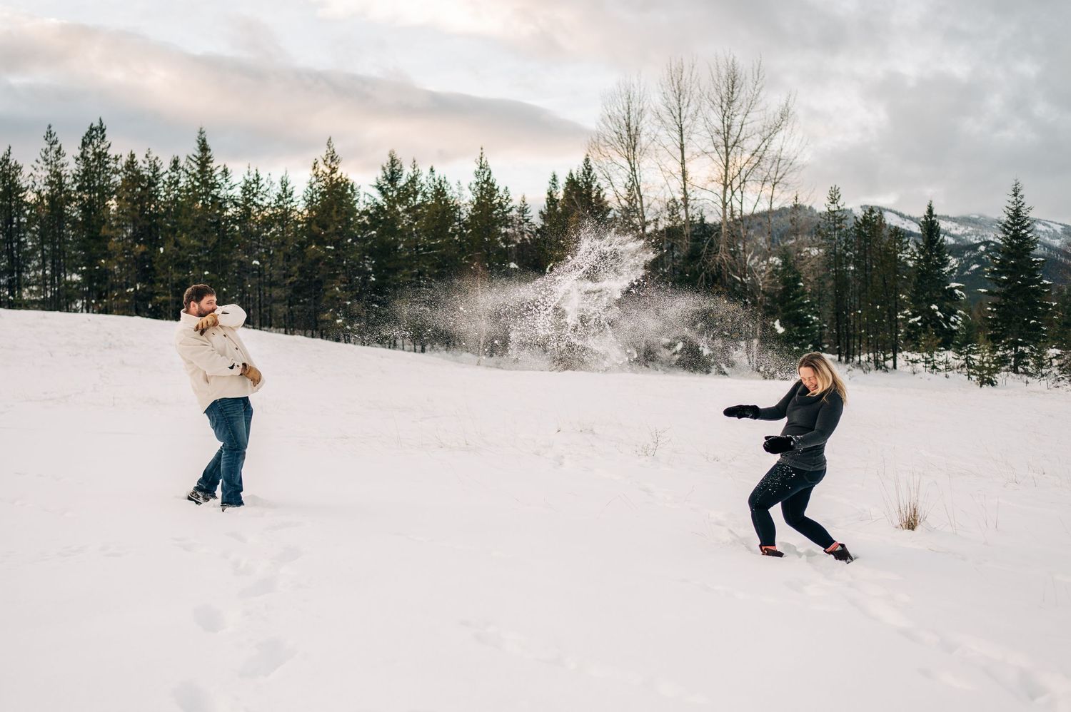A group of people having a playful snowball fight in a snowy winter forest landscape.