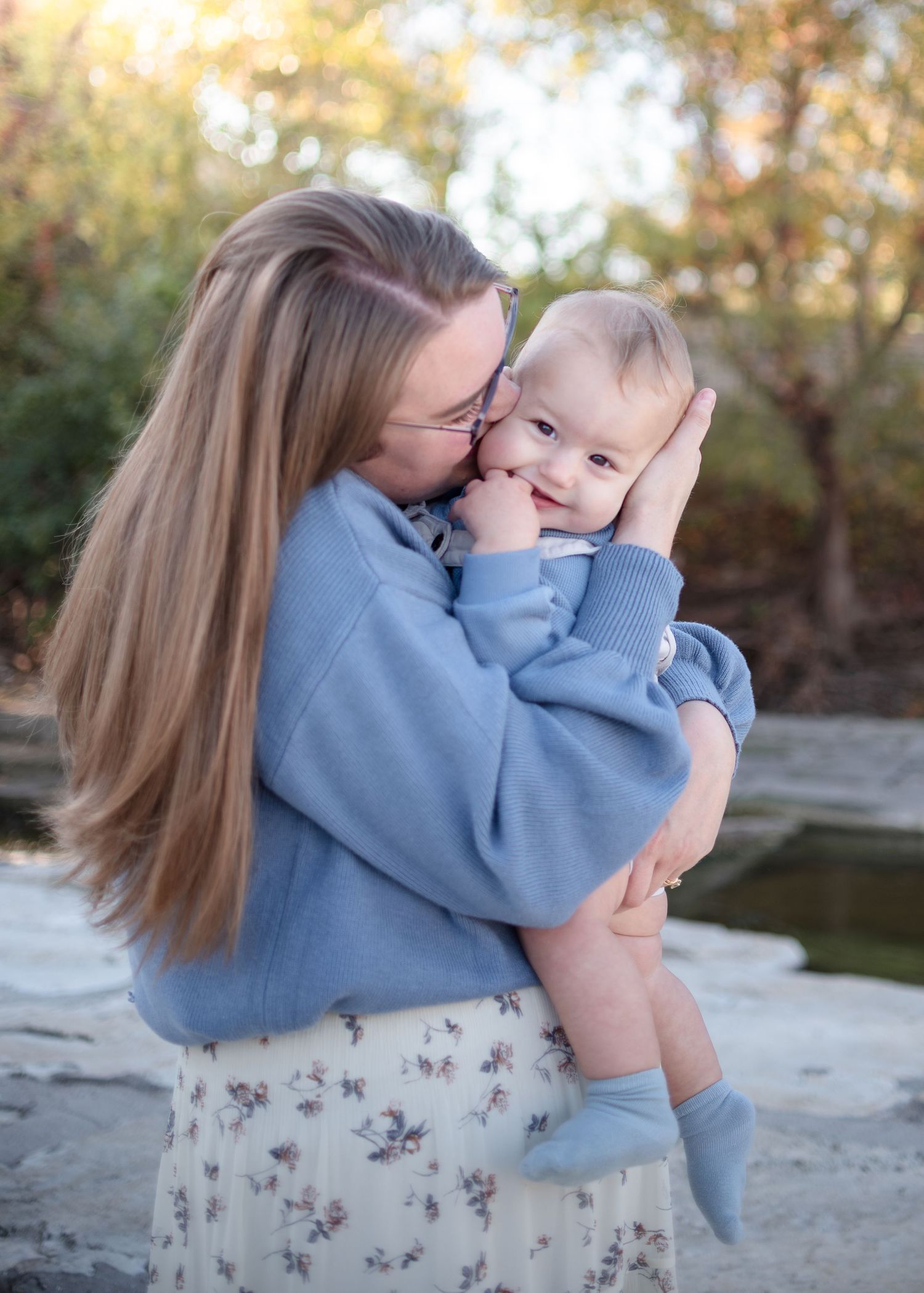 Mother kissing baby during outdoor family session at Nolan Creek in Belton Texas