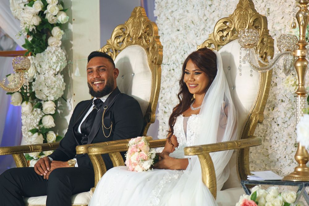 Elegant wedding reception setup with ornate gold chairs, white floral arrangements, and romantic decor details.