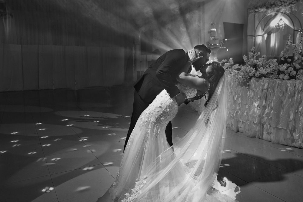 Black and white wedding dance floor scene with dramatic lighting and flowing bridal gown.