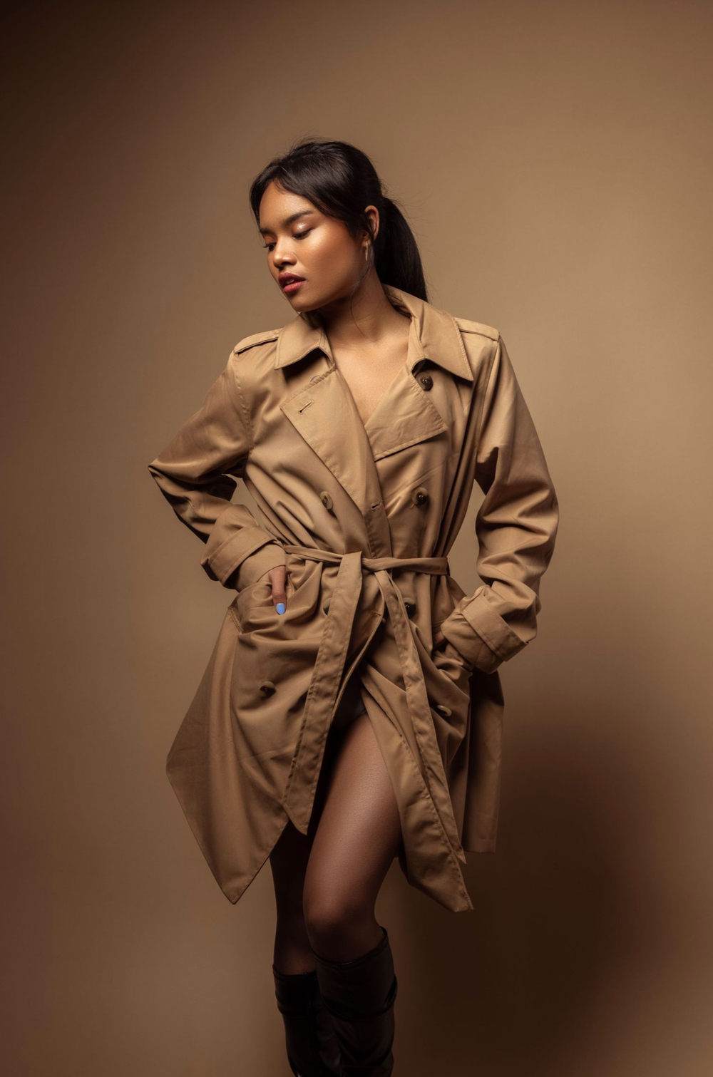 Fashion editorial featuring oversized beige trench coat styled in various dramatic poses against brown backdrop.