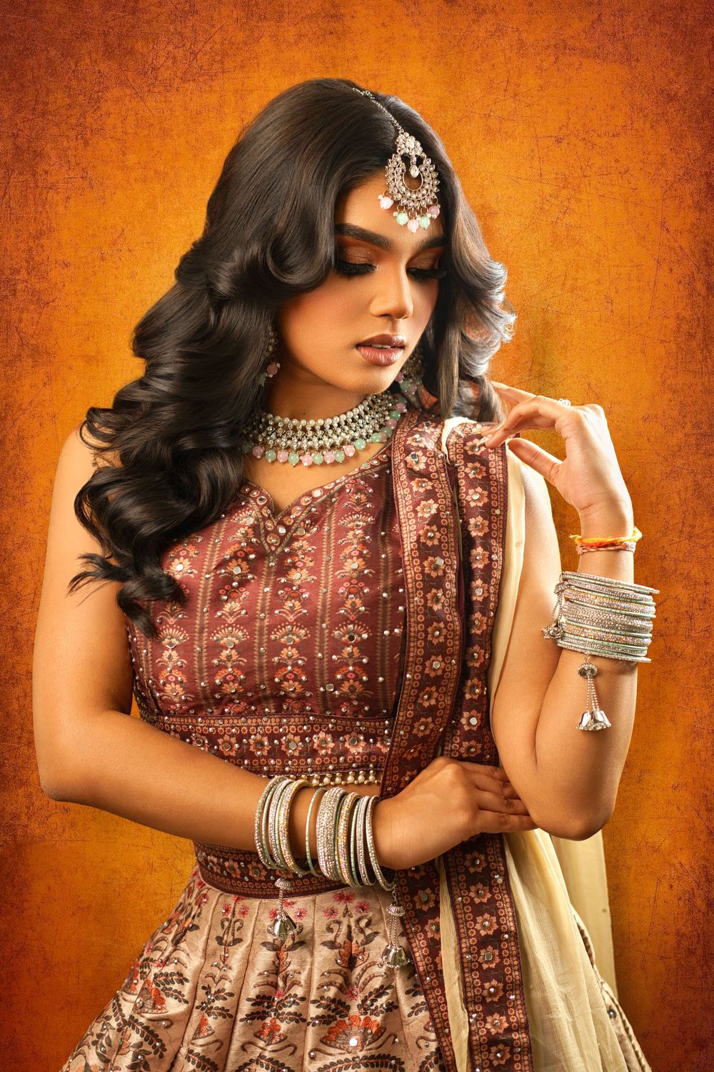 Elegant South Asian bridal fashion photoshoot featuring traditional burgundy lehenga with intricate embroidery and silver jewelry.