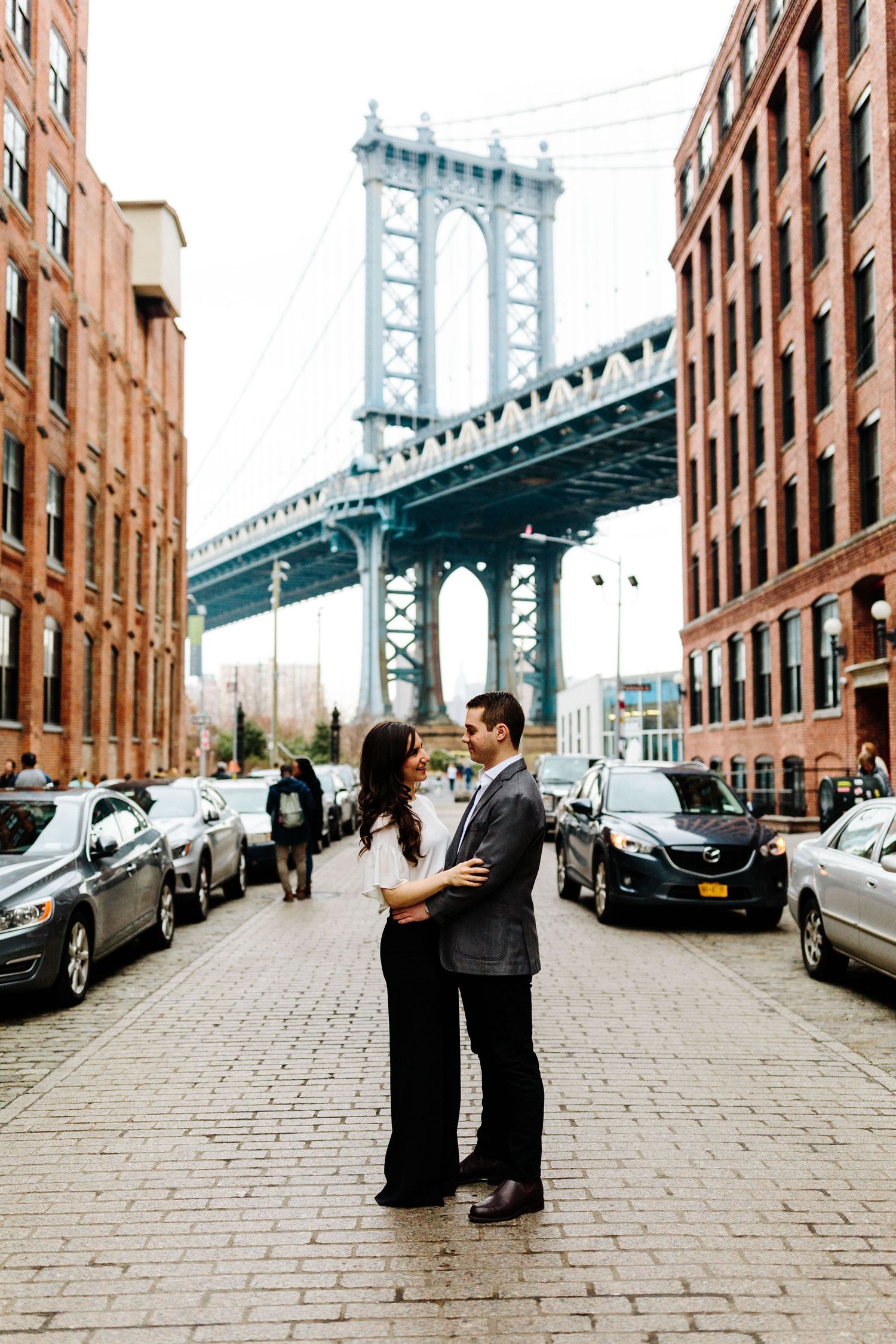 Romantic couple photos on cobblestone street with iconic Manhattan Bridge view.