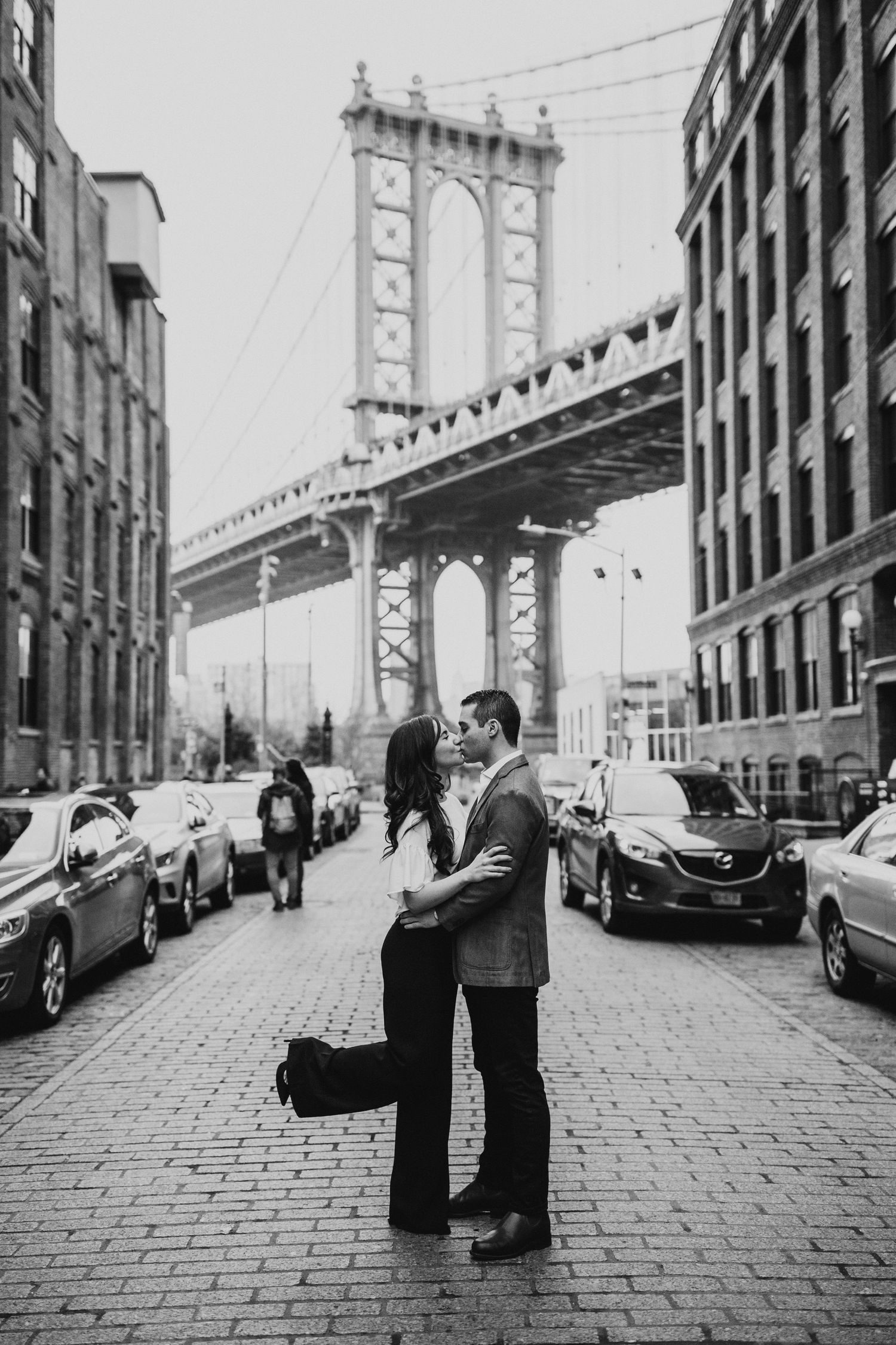 Black and white urban portrait with Manhattan Bridge and historic buildings in DUMBO.
