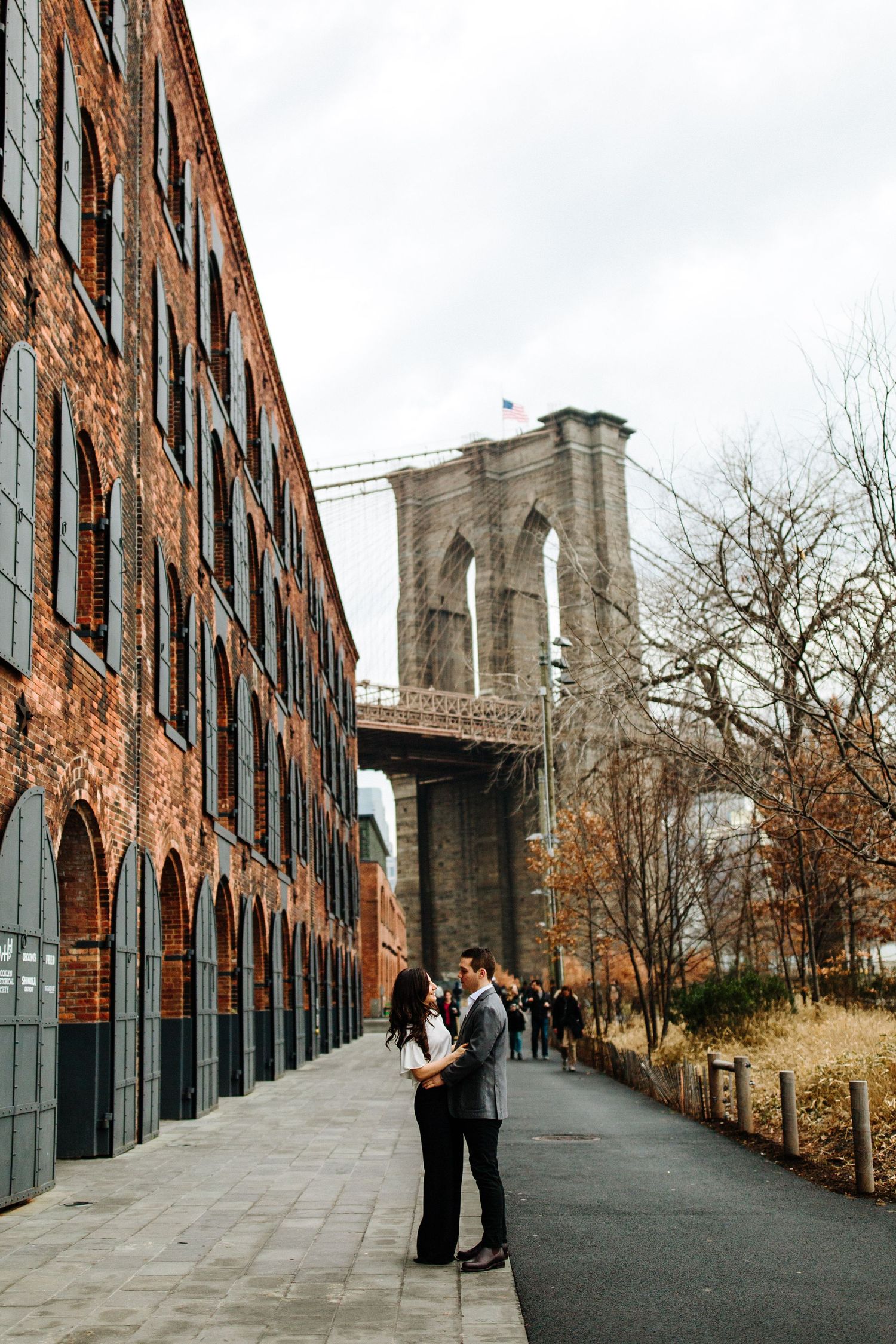 Historic brick buildings line path leading to Brooklyn Bridge in DUMBO neighborhood.