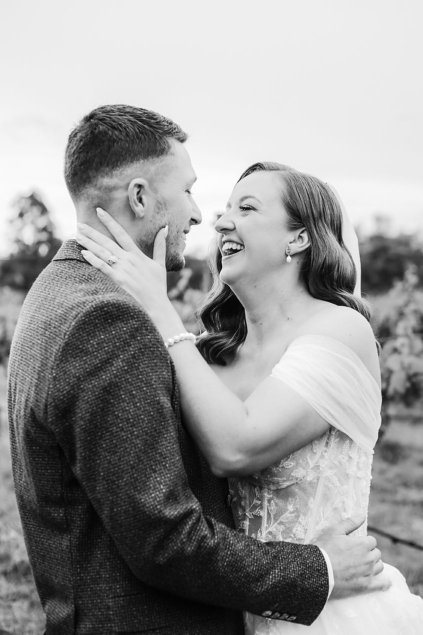 A joyful couple shares an intimate embrace and laugh together in a series of black and white outdoor portraits.
