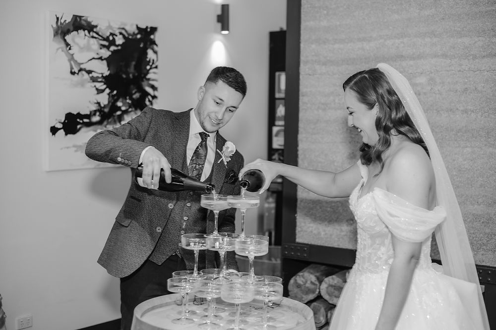 A black and white photo series showing a couple pouring champagne into a tower of glasses during a wedding celebration.