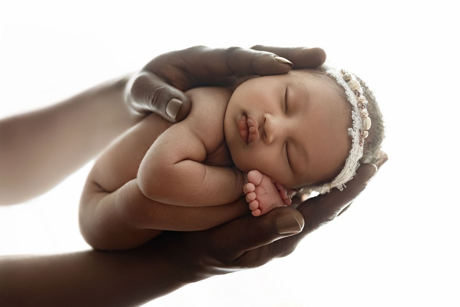 Fine art newborn photography in Houston. Artistic photo of sleeping baby held in hands, professional newborn photographer Paloma Schell Katy
