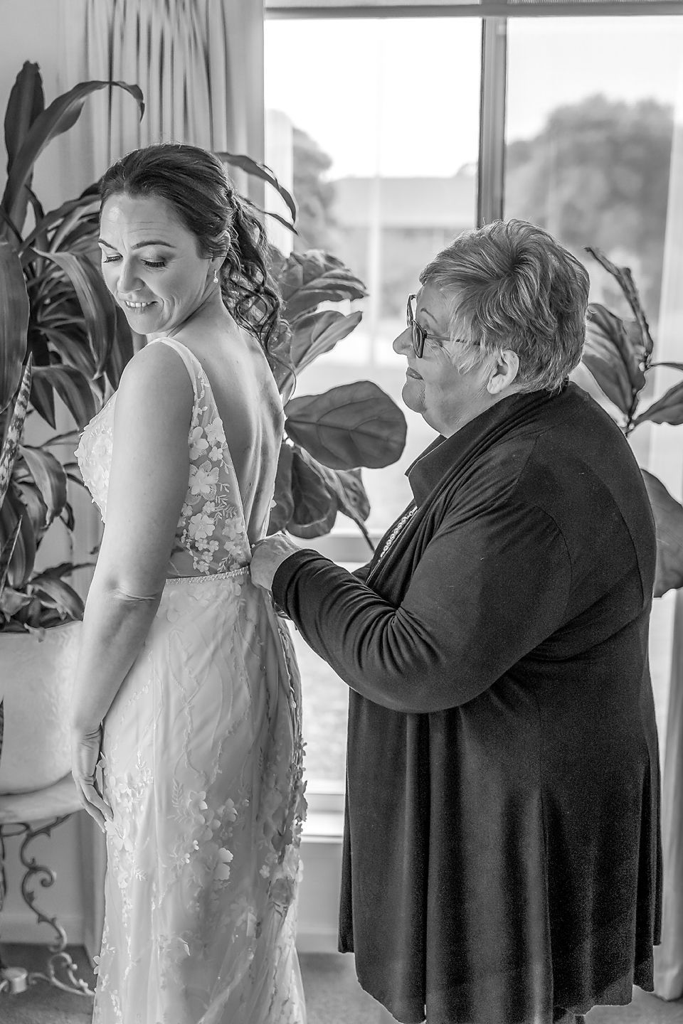 Black and white photo sequence showing an emotional moment at a wedding as people embrace in formal attire.
