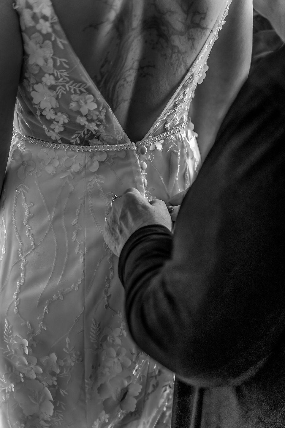Close-up detail of a delicate lace wedding dress back with intricate patterns in black and white.
