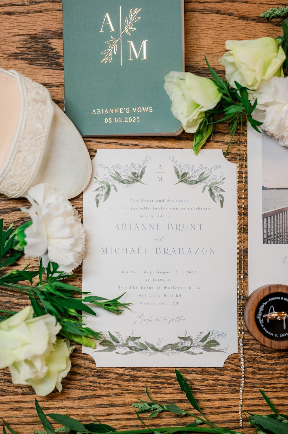 Elegant wedding invitation suite with monogram design and white roses on rustic wooden background.