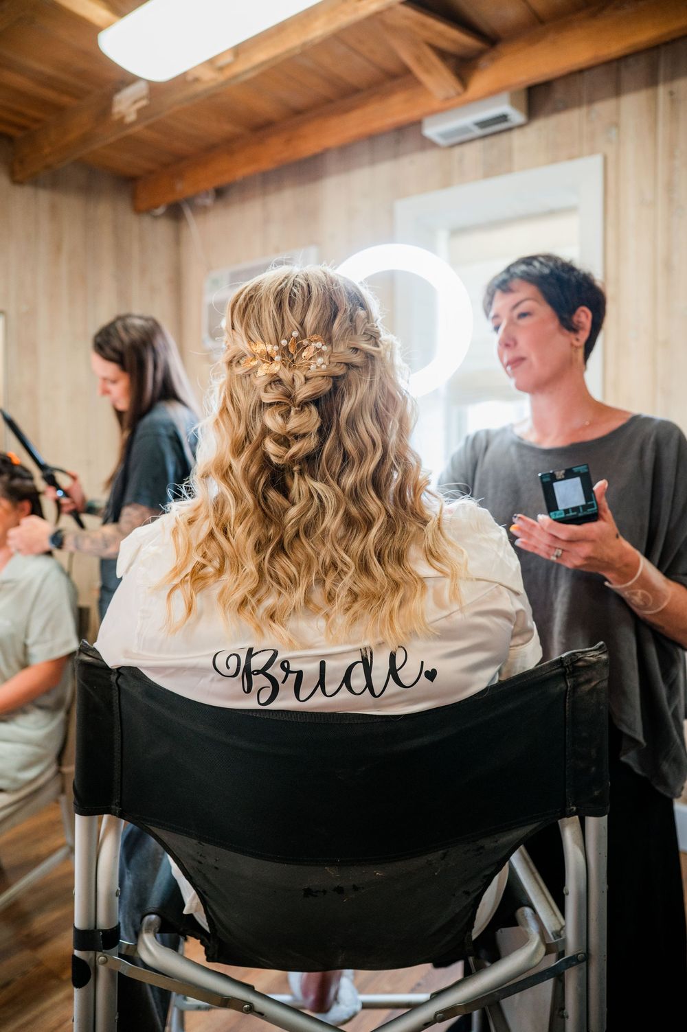 Hair styling session in progress with black robe showing 'Bride' text on the back.