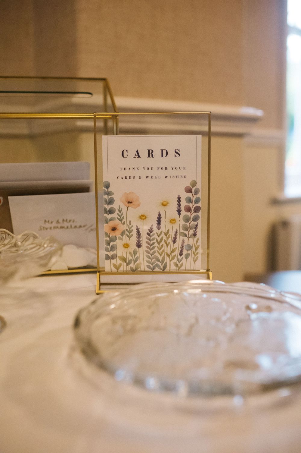 Wedding greeting cards and stationery displayed on a white table with floral designs and gold accents.