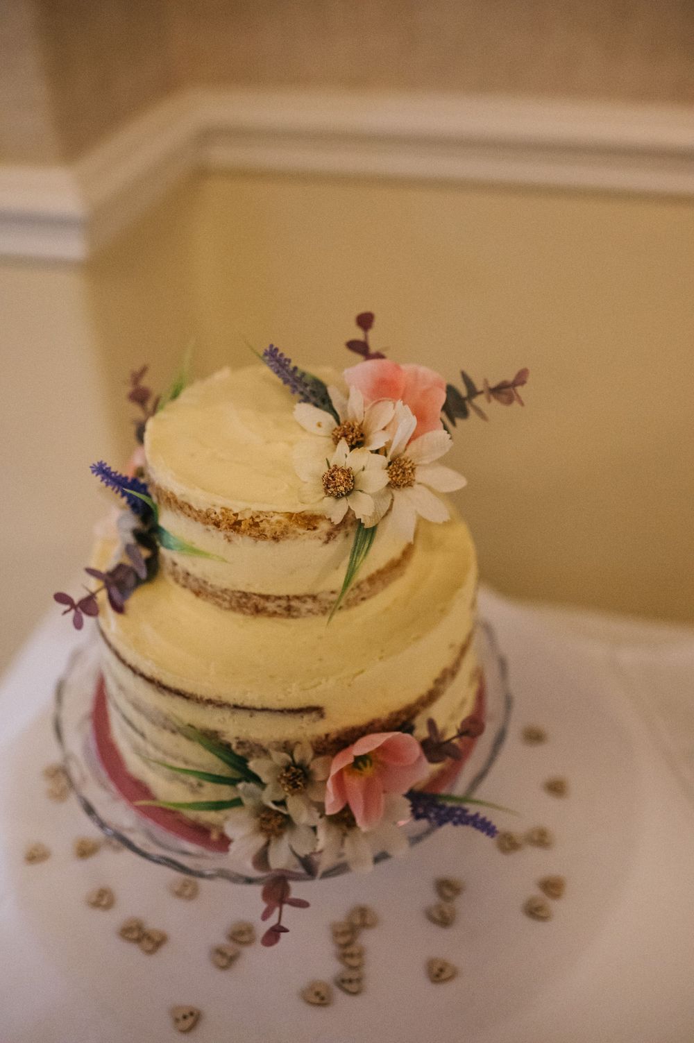 Wedding cake decorated with delicate fresh flowers and lavender on cream frosting.