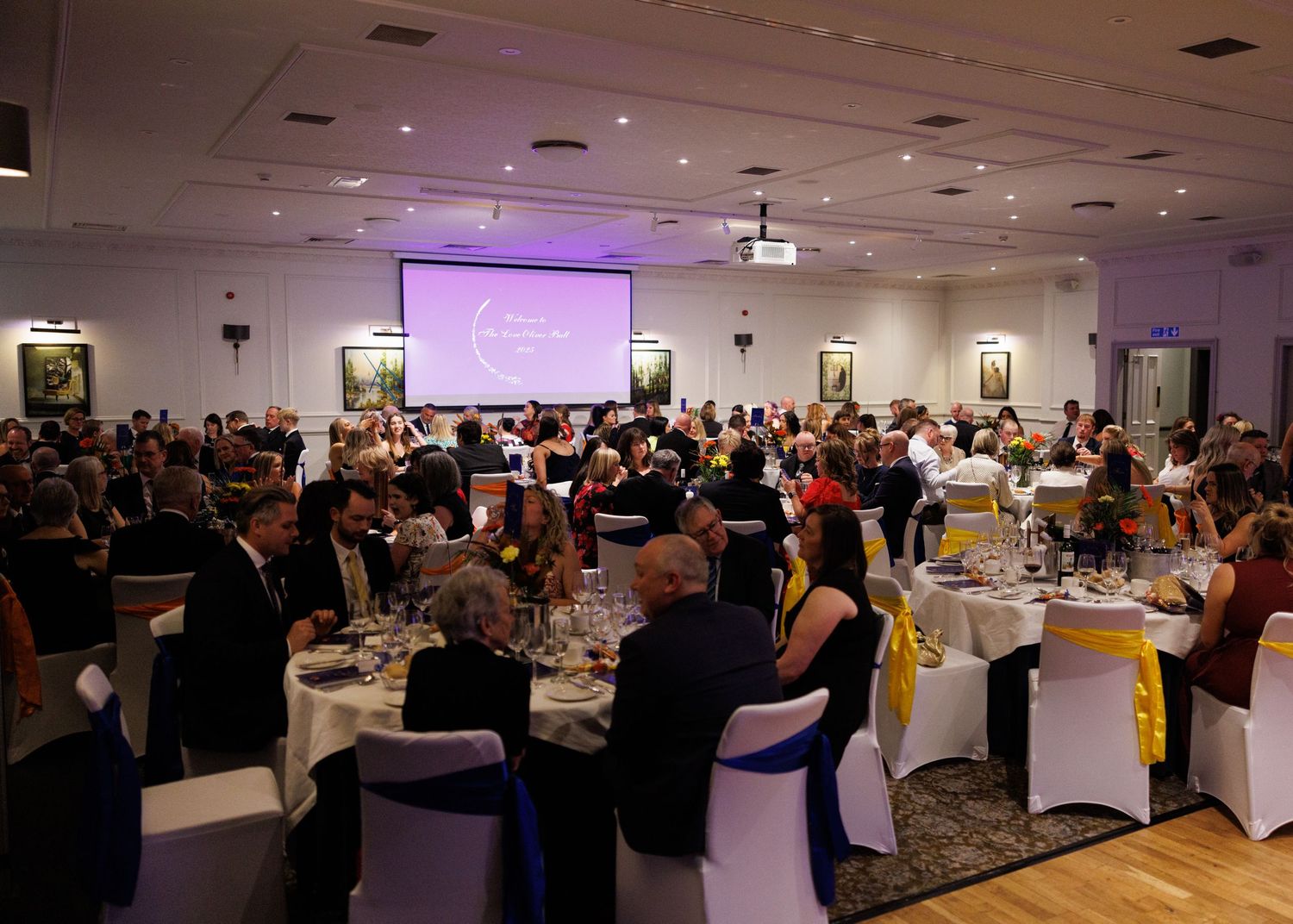 Large banquet hall filled with guests seated at round tables for a formal evening event.