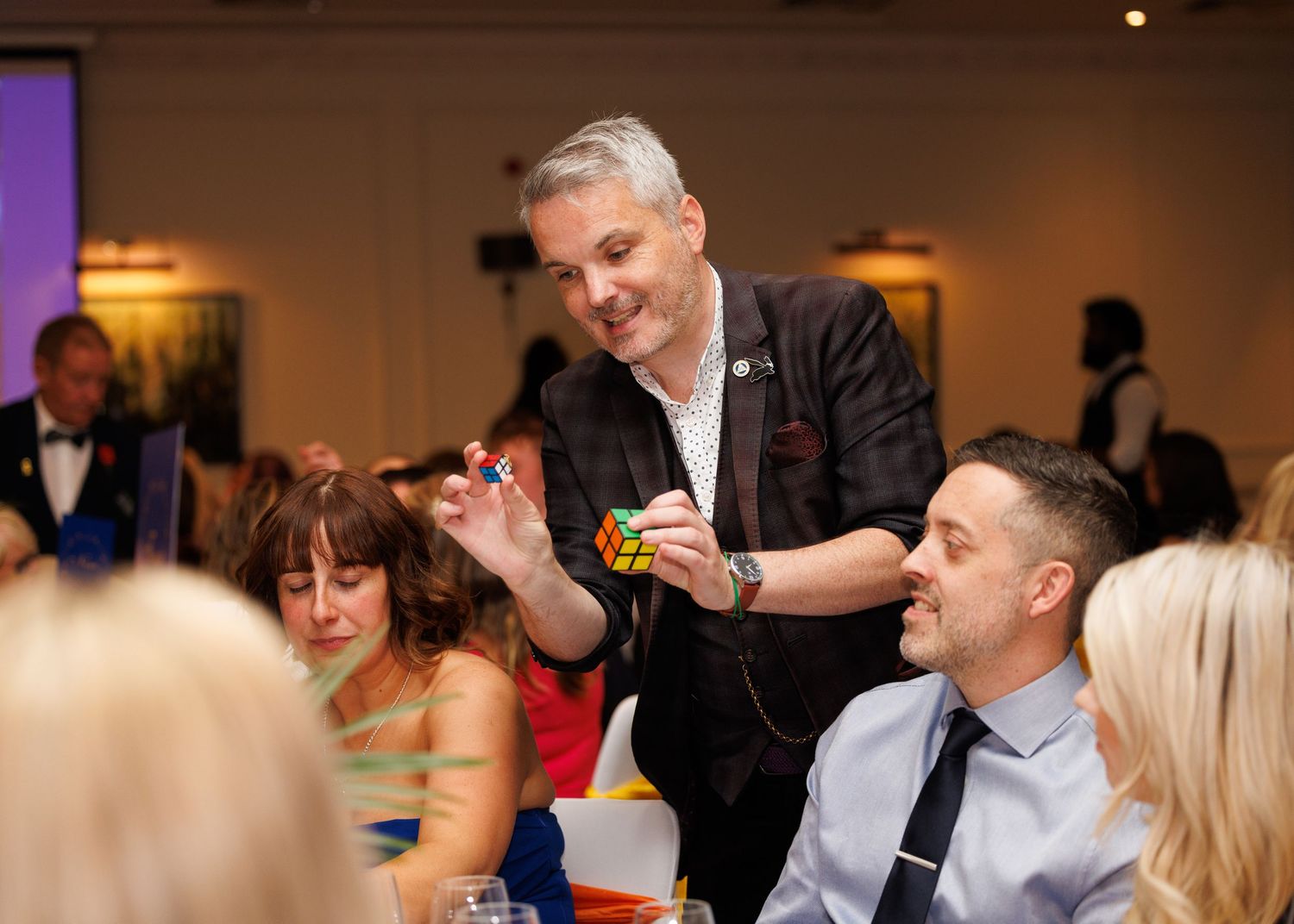 Guests enjoying themselves and socializing at an indoor event with warm lighting and formal attire.
