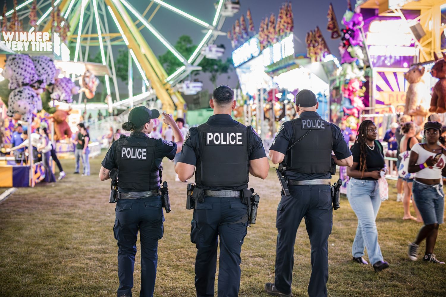 Law enforcement officers monitoring crowd safety at carnival fairgrounds.