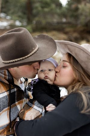 Parents kissing their baby’s cheeks during an intimate family photography session