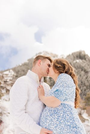 Pregnant couple embracing during winter maternity photos in the Utah mountains