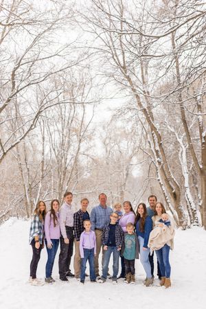 Large family portrait standing together in a snowy forest during a winter family photo session