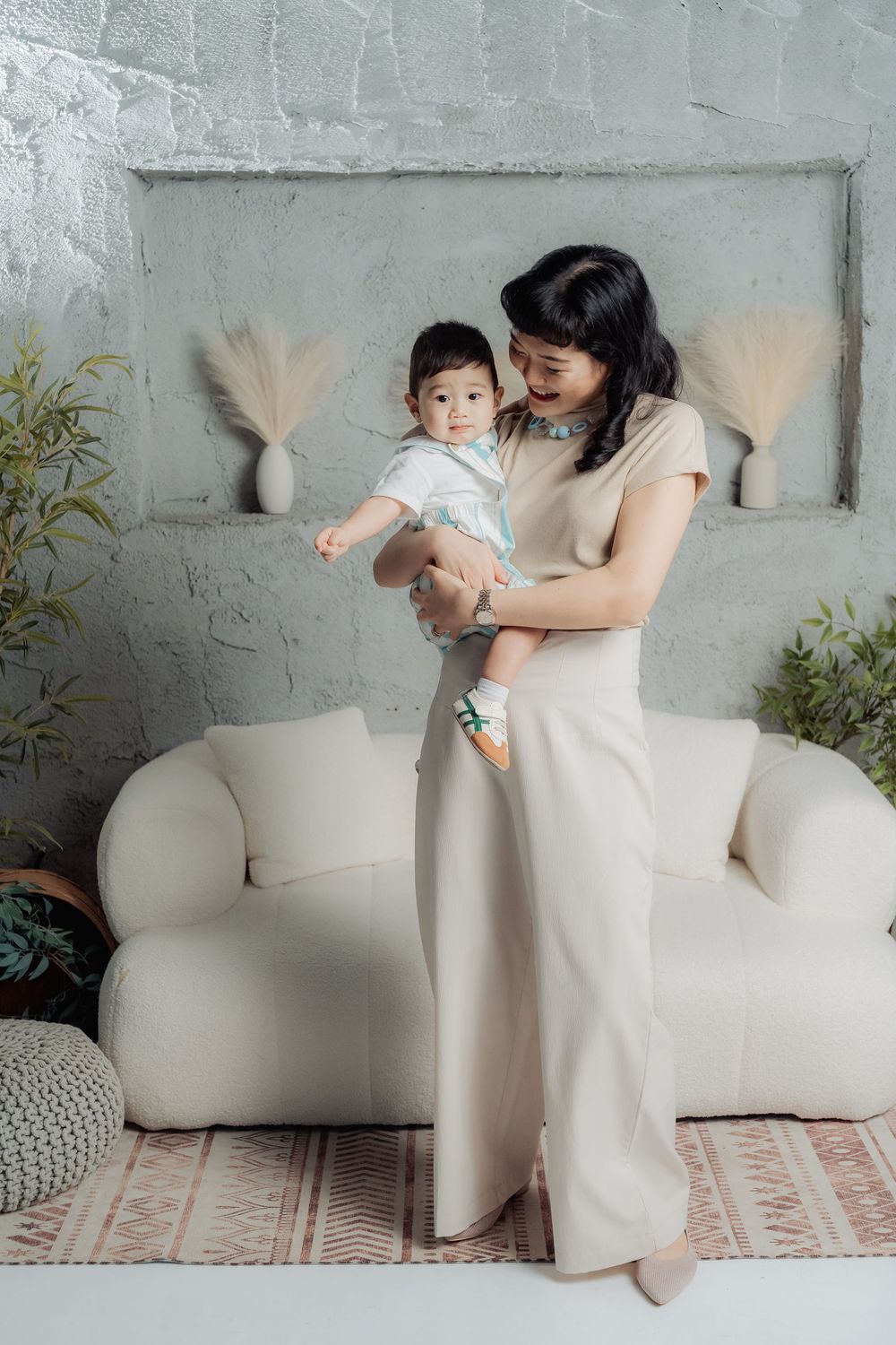 A tender family moment captured in a series of photos against a gray wall with white furniture.